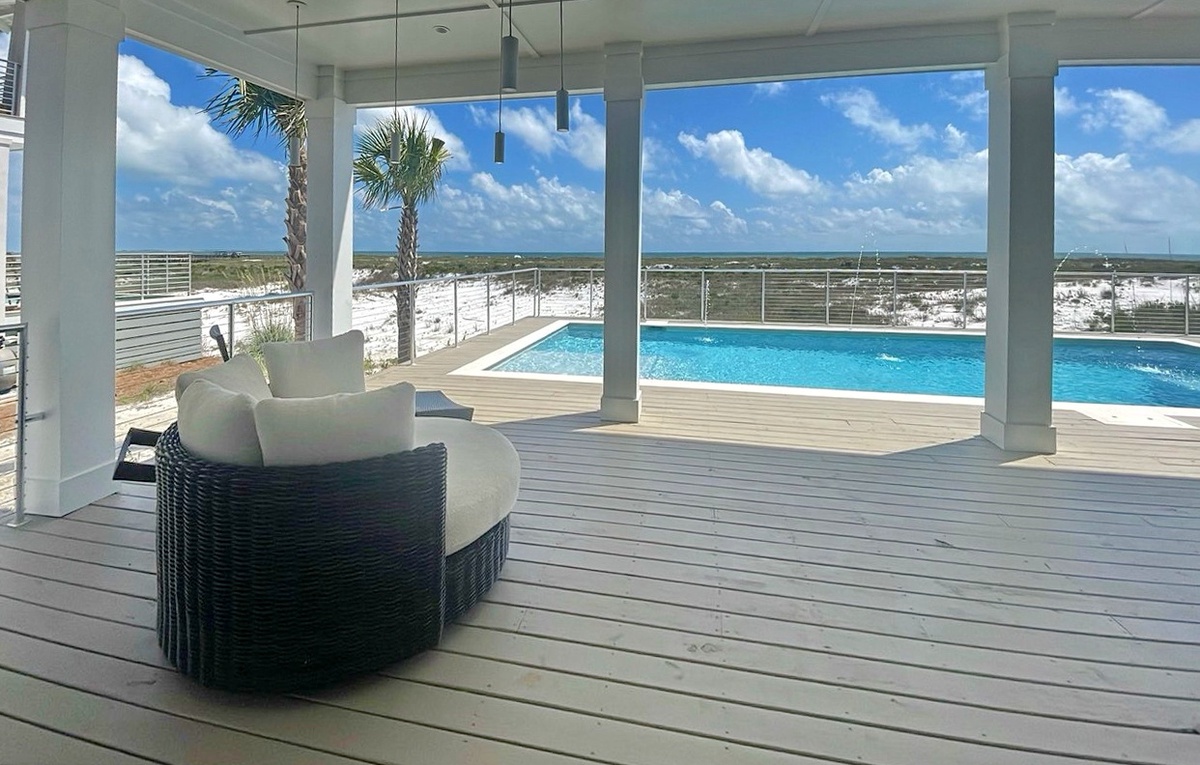 Relax in your shaded patio lounge while gazing out at the sparkling pool, white sand dunes, and endless coastal views stretching to the horizon.