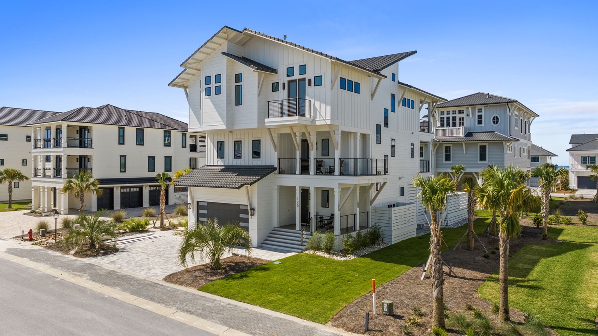 A stunning contemporary beach house featuring multiple levels, spacious balconies, and tropical landscaping with palm trees. The property sits in a well-maintained coastal neighborhood perfect for your vacation getaway.