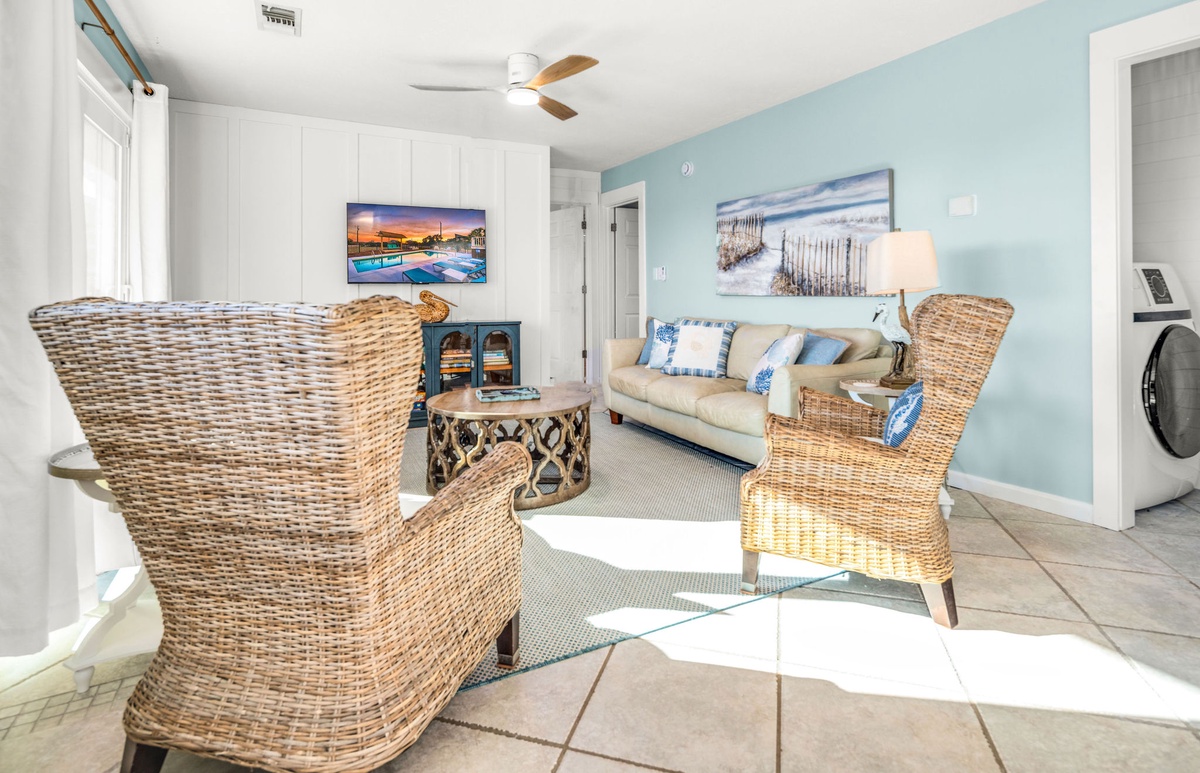Unwind in your coastal-inspired living room with plush seating, soothing sea views artwork, and modern amenities including convenient laundry access.
