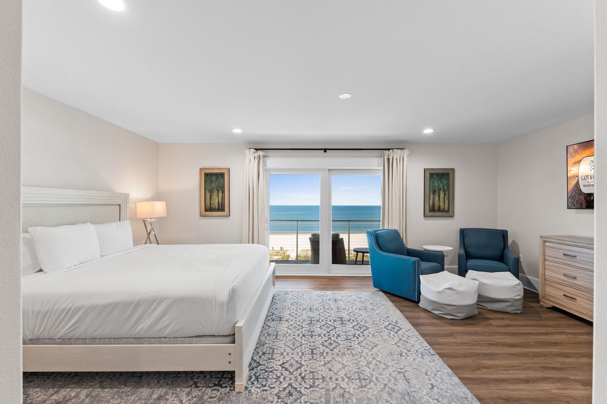 Wake up to stunning ocean views through sliding glass doors opening to your private balcony. Sink into crisp white linens while turquoise armchairs invite you to unwind and soak in the coastal tranquility.