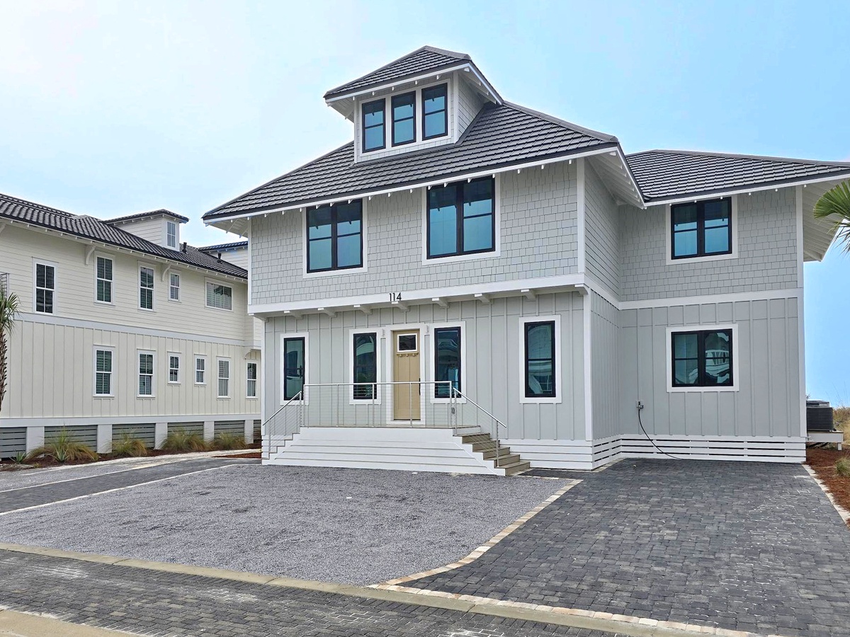 Elegant coastal-style home featuring modern shingle architecture and spacious design in a well-appointed neighborhood setting.