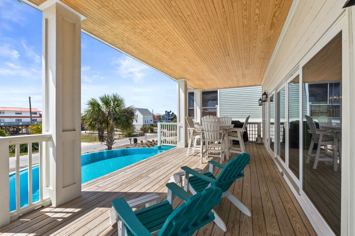 Relax on your private covered deck with colorful Adirondack chairs overlooking the sparkling pool—your perfect spot for morning coffee or evening unwinding.