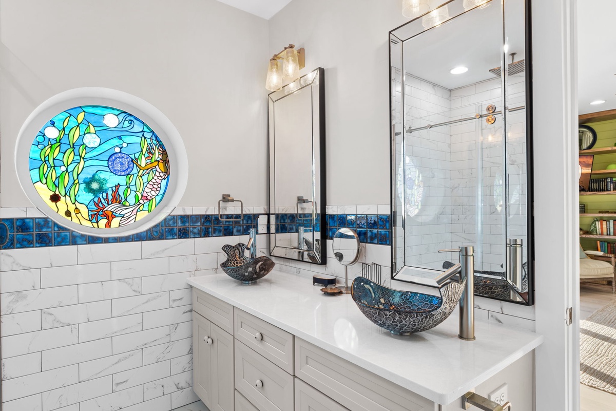 Your private bathroom features dual sinks and a stunning underwater-themed stained glass window that transforms your daily routine into an artistic experience.