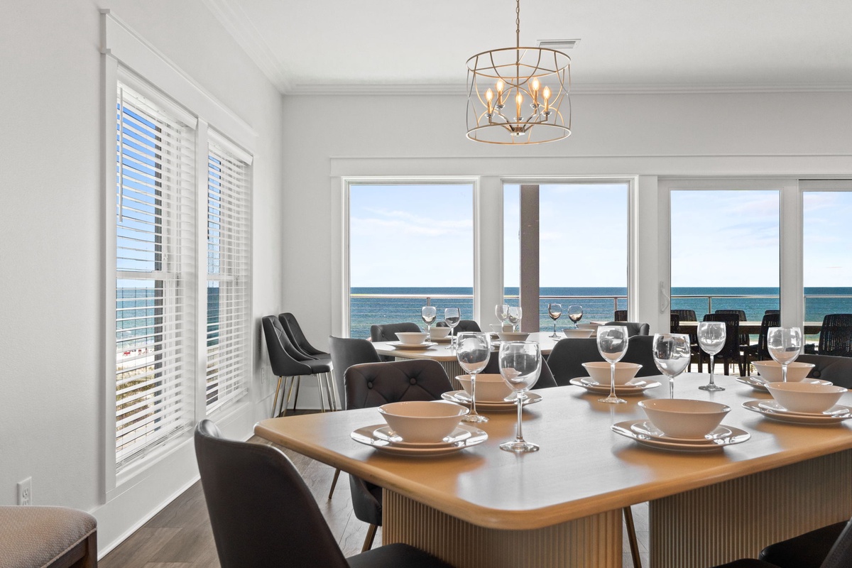 Gather around this elegant dining table where every meal comes with stunning ocean views through floor-to-ceiling windows. Natural light fills the space, creating perfect moments for your group.