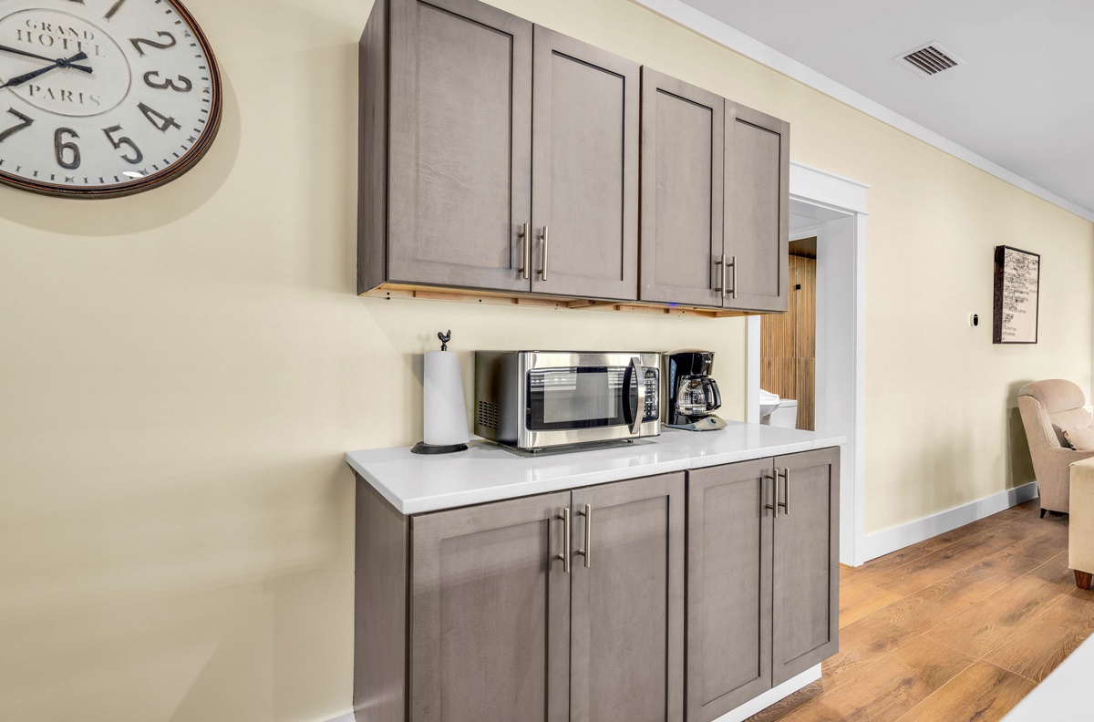 Your well-appointed kitchenette features sleek gray cabinetry, microwave, and coffee maker for convenient meal prep during your stay.