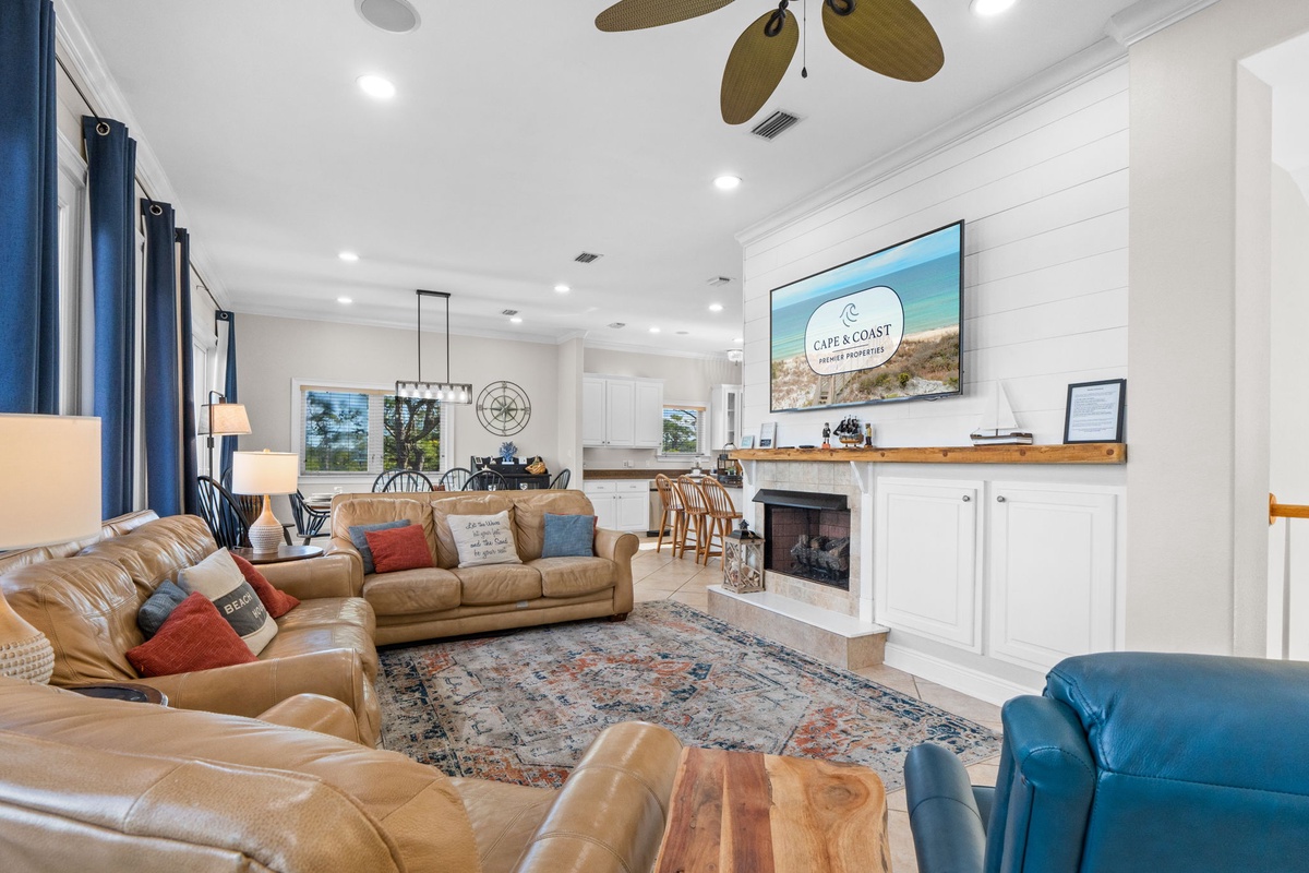 Sink into plush leather sofas in your spacious living area, where coastal charm meets comfort with a crackling fireplace and open kitchen.