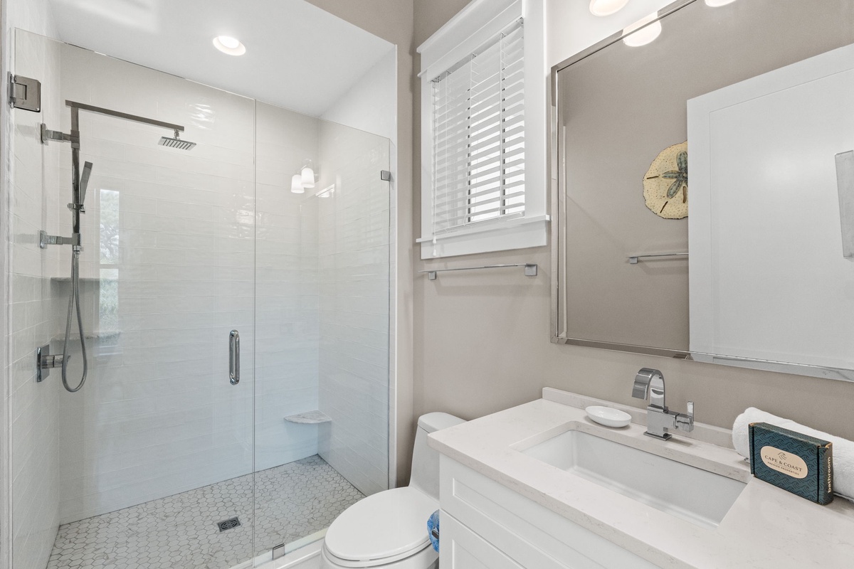 Your private bathroom welcomes you with clean white tiling, modern fixtures, and a spacious glass shower for refreshing mornings or relaxing evenings.