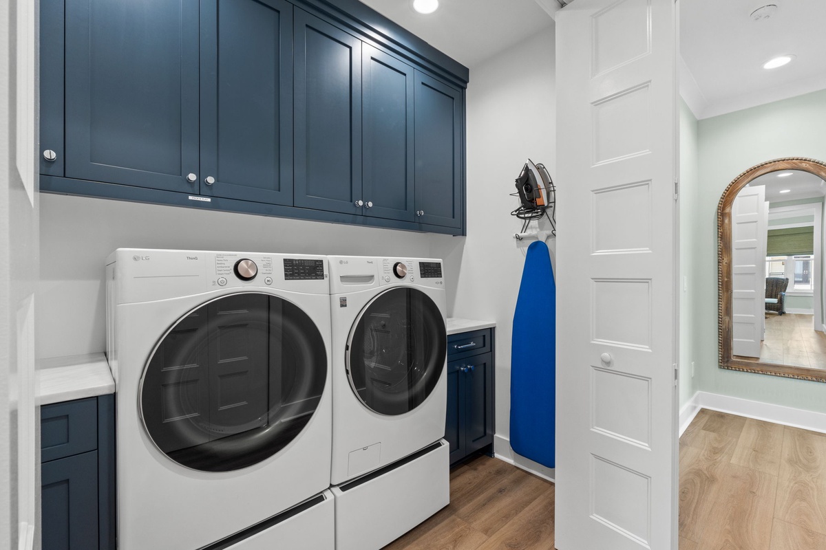 Your in-home laundry room features modern front-loading appliances beneath custom cabinetry, with an ironing station ready for your convenience.