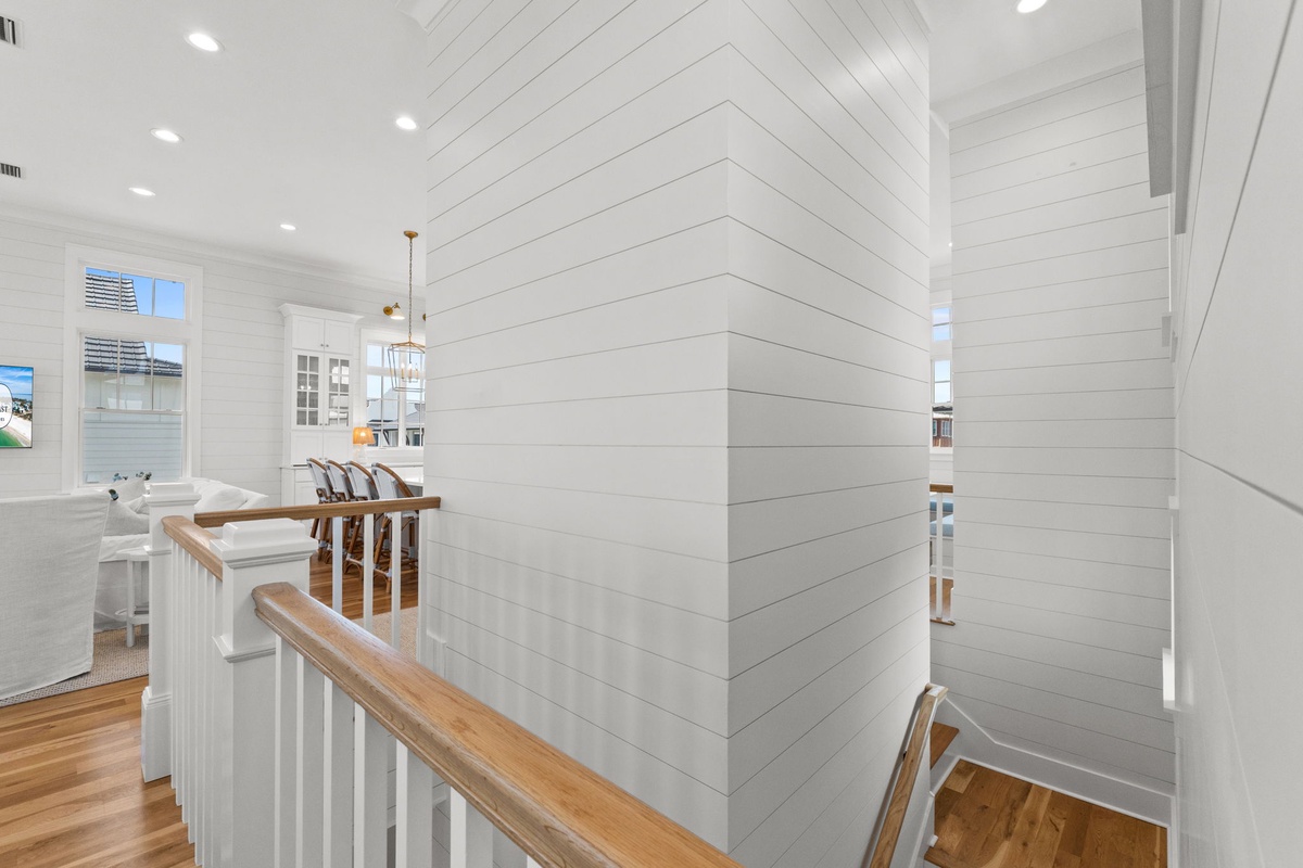 Bright shiplap walls and warm wood tones create a welcoming coastal charm where your upstairs and downstairs living spaces flow seamlessly together.