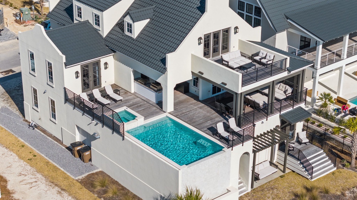 Stunning beachfront property featuring elegant white architecture with private pool and expansive outdoor living spaces.