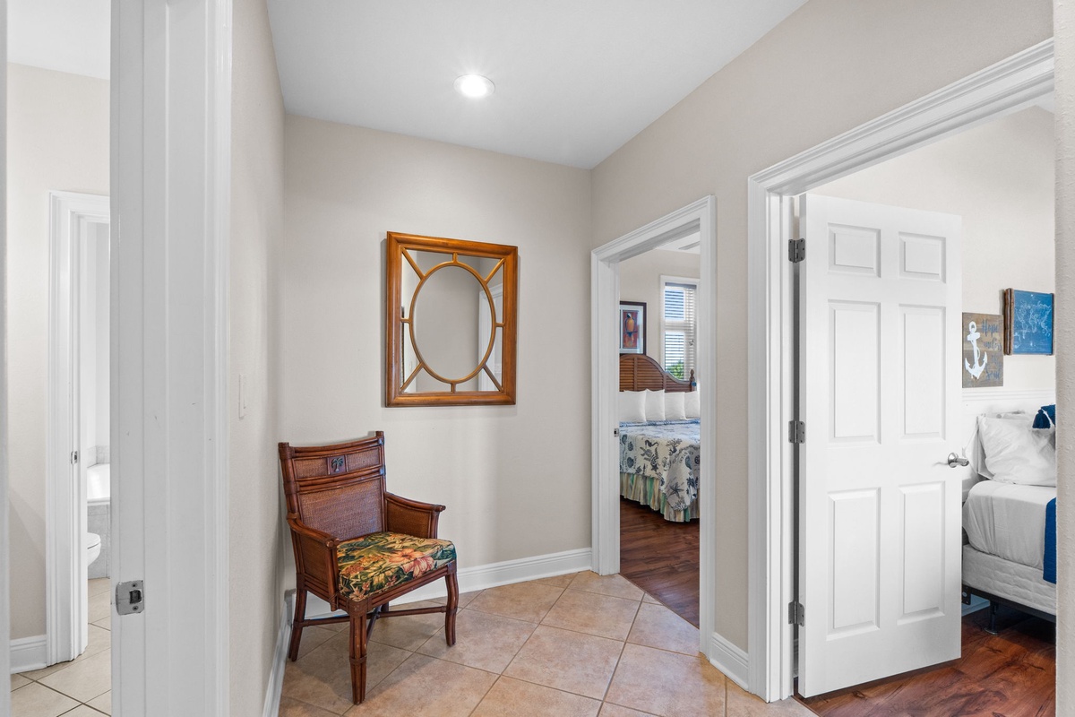 Step into your welcoming hallway featuring elegant tile floors, charming vintage chair, and glimpses of comfortable bedrooms awaiting your arrival.