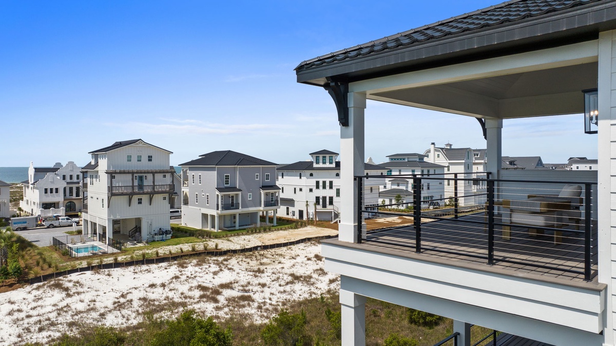 A beachside residential community featuring modern coastal architecture with varied building styles, located near white sandy shores.
