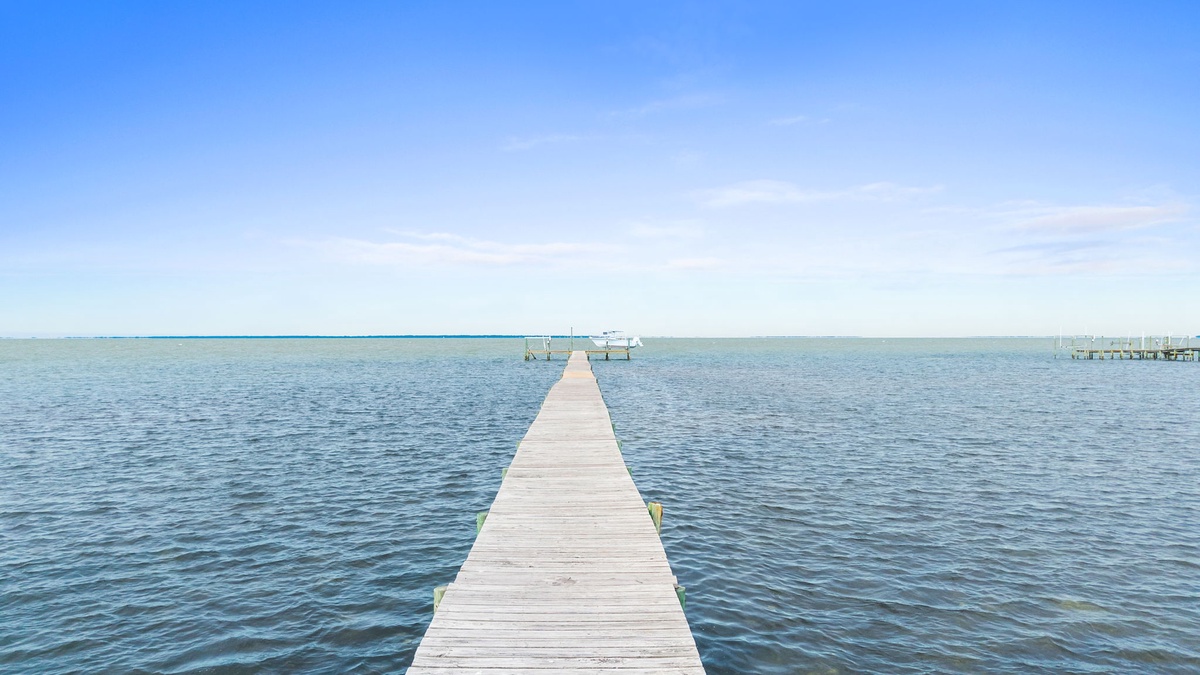 Peaceful waterfront setting with a private dock extending into calm waters under blue skies.