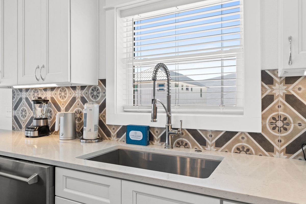 Your modern kitchen features a sleek undermount sink with a professional-style faucet, complemented by stylish patterned tile backsplash and bright natural light.