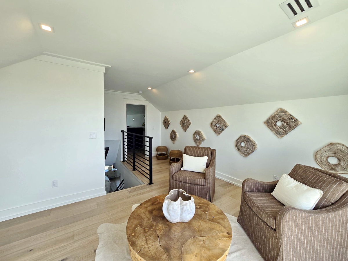 Unwind in your bright upstairs retreat with cozy wicker seating and natural woven art creating a peaceful coastal vibe.