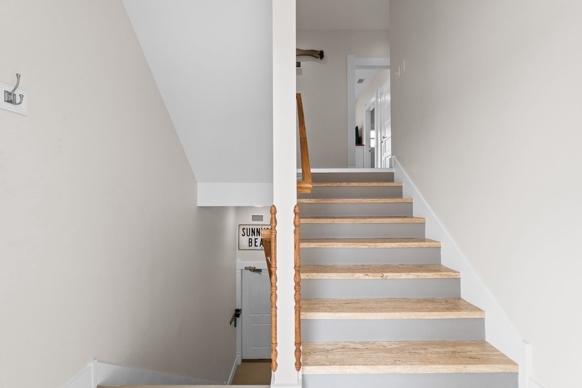 Your coastal retreat features beautiful wood-toned stairs leading to private upstairs spaces, with charming details throughout.