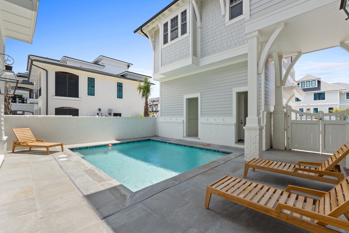 Slip into your private pool oasis, where sun-drenched loungers await on spacious pavers. Feel the cool water invite you to float away while coastal breezes drift through your secluded retreat.