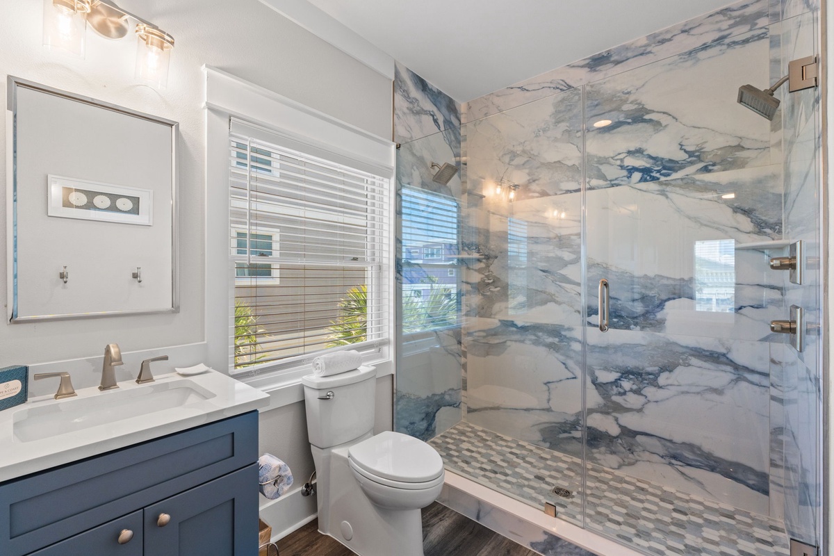 Your private bathroom features stunning blue-veined marble walls, a spacious walk-in shower, and elegant finishes that create a spa-like retreat for your stay.