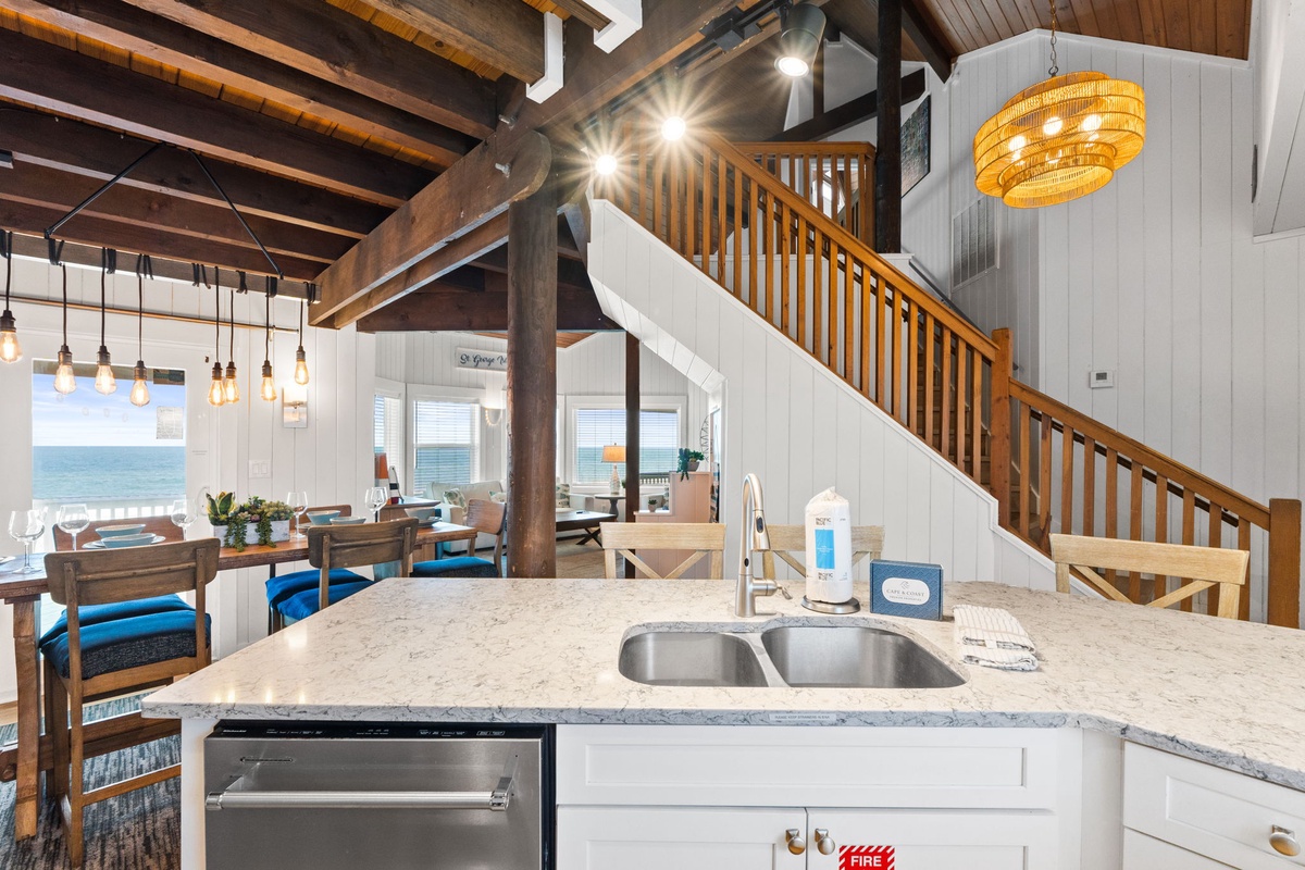 Step into your open-concept retreat, where warm wood beams soar overhead and a stunning ocean view frames your stay. The kitchen invites you to gather and unwind while natural light spills across every corner.