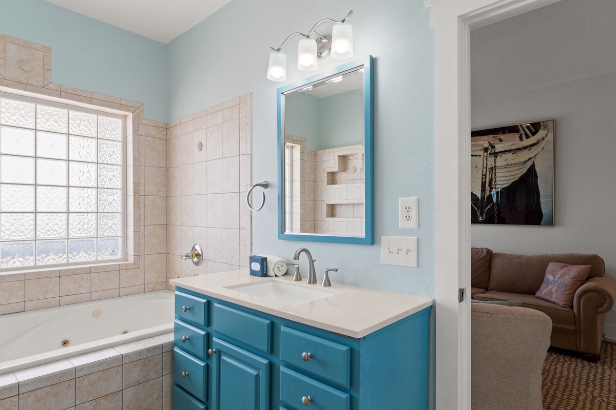 Refresh in a bright bathroom with a teal vanity, jetted tub, and soothing coastal colors that make every moment feel like a mini retreat.