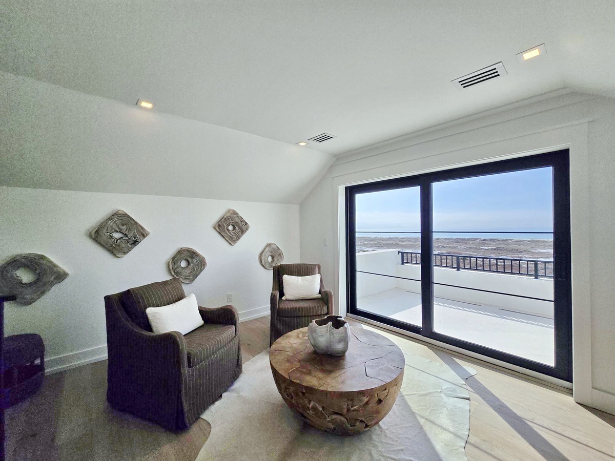 Relax in your private oceanfront seating area with stunning sea views through floor-to-ceiling windows, complete with comfortable wicker chairs and coastal decor.