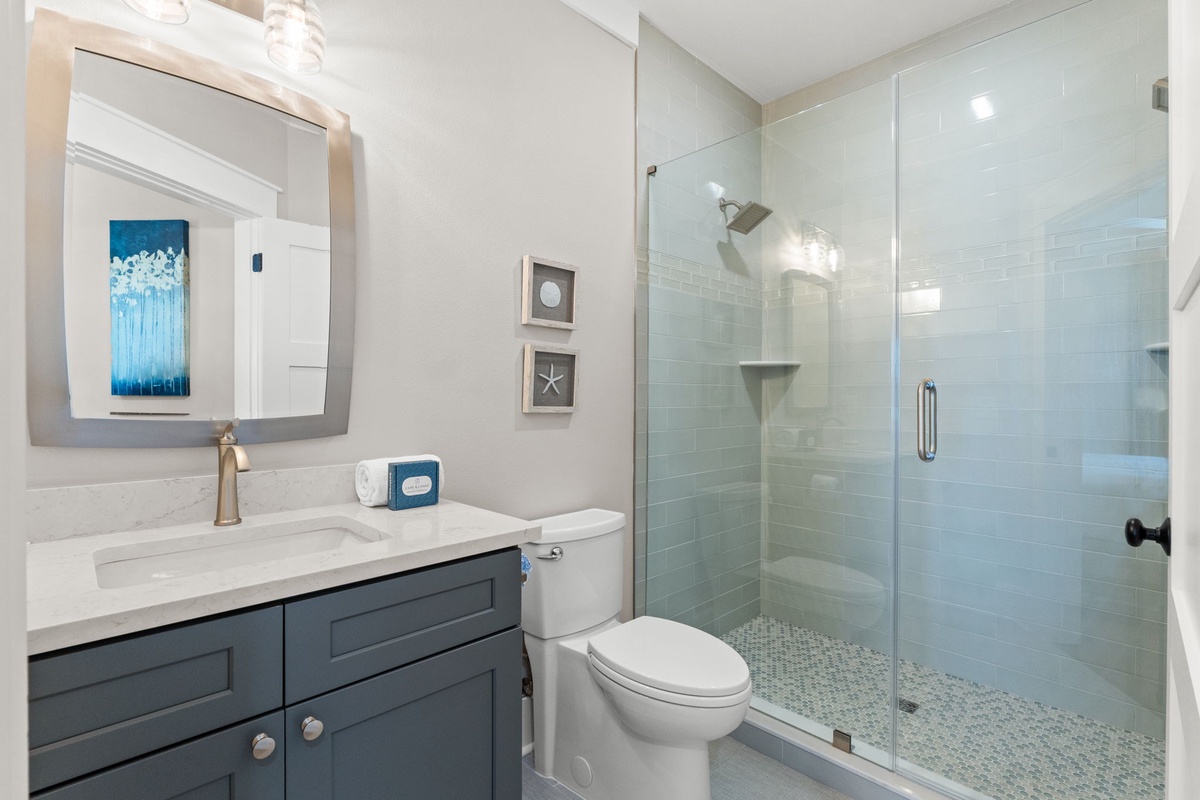 Step into a beautifully refreshed bathroom with soft coastal charm, featuring a walk-in glass shower, elegant vanity, and soothing blue accents that invite your seaside getaway.