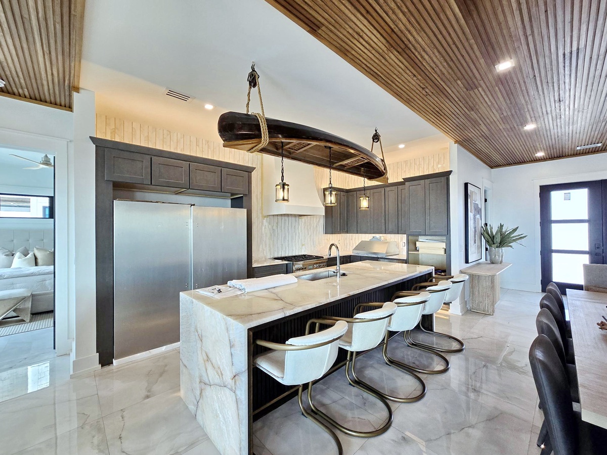 Prepare your favorite dishes in this stunning kitchen with waterfall island, stainless appliances, and boat-inspired chandelier.