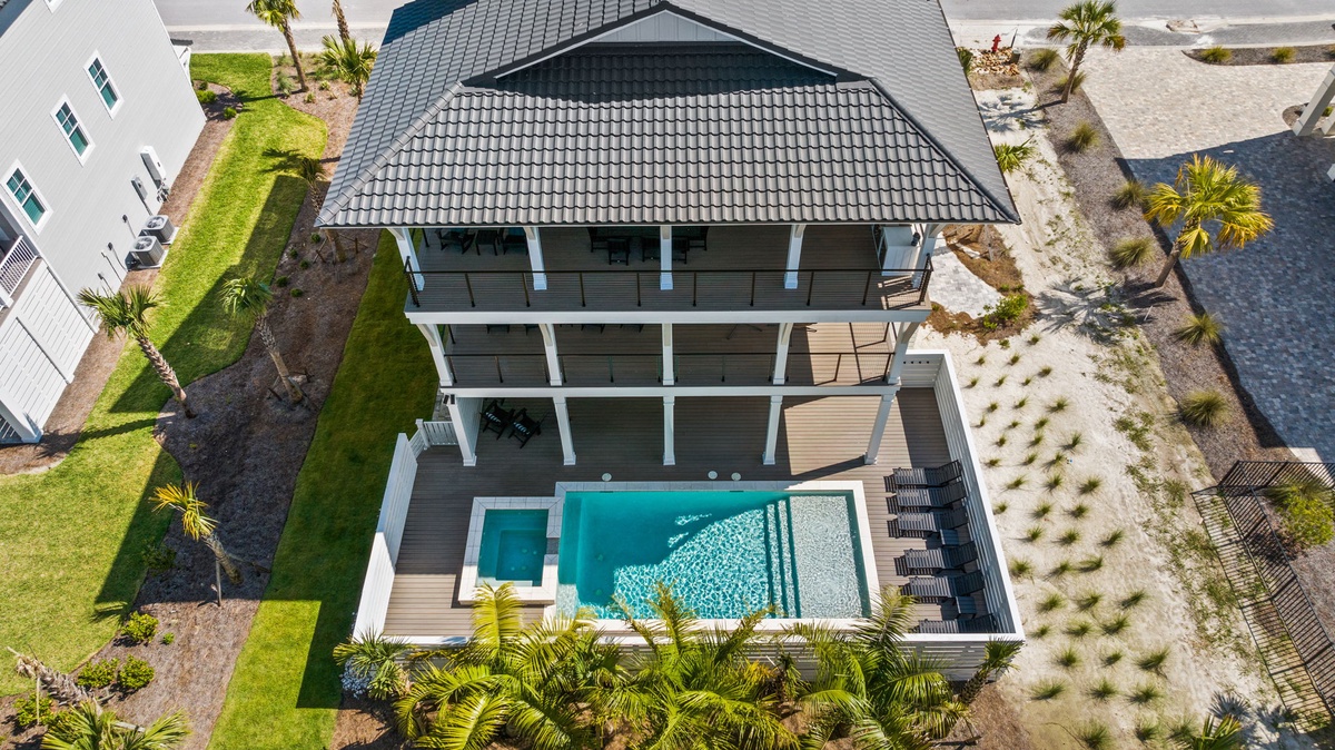 Aerial view showcases the property's multi-level architecture with a private pool, tropical landscaping, and spacious outdoor deck areas, situated just steps from the beachfront neighborhood.