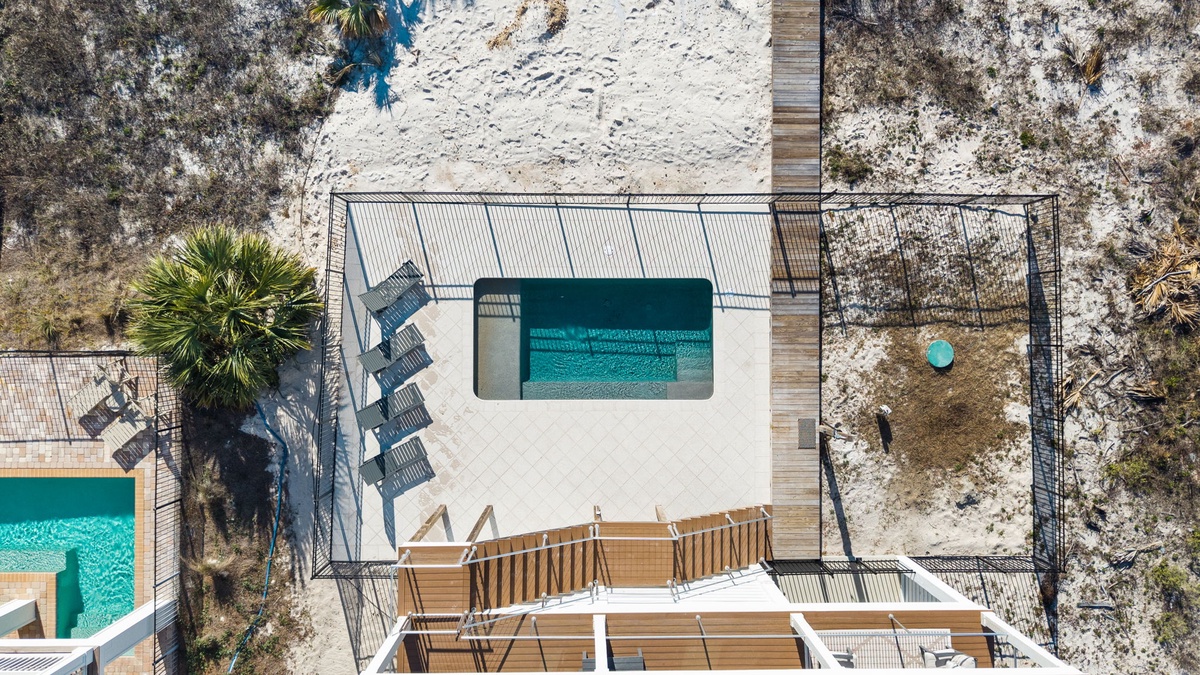 Aerial view of the property showcasing the pristine swimming pool, sun loungers, and tropical palm surrounded by natural landscape.