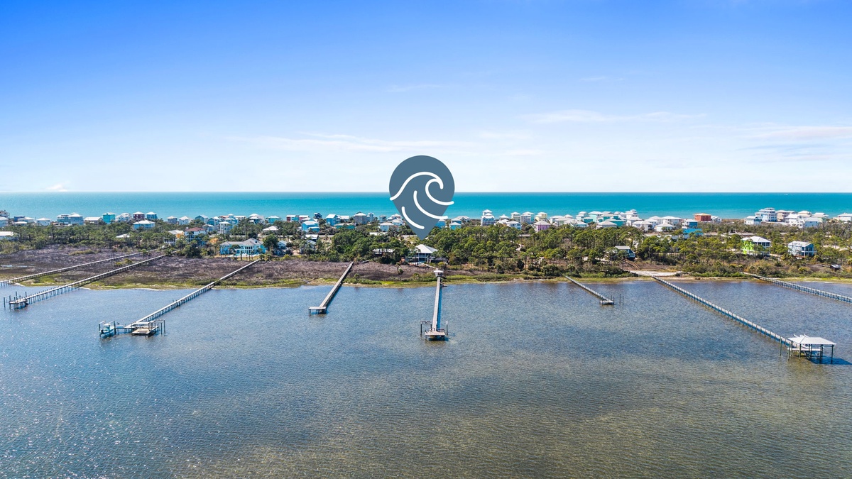 Aerial view of a coastal community with waterfront homes, marina docks, and pristine beach access.