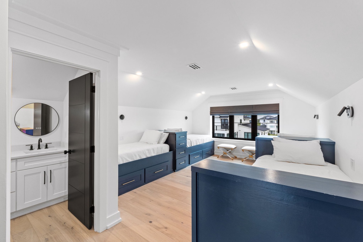 Gather the family in this bright, spacious bedroom featuring two cozy beds with navy storage drawers. Your private ensuite makes mornings easy, while built-in seating by the window invites you to relax and unwind.