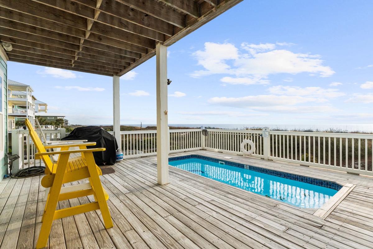 Dive into your private pool on this expansive deck, complete with BBQ and bright yellow chair for sunny afternoon relaxation.