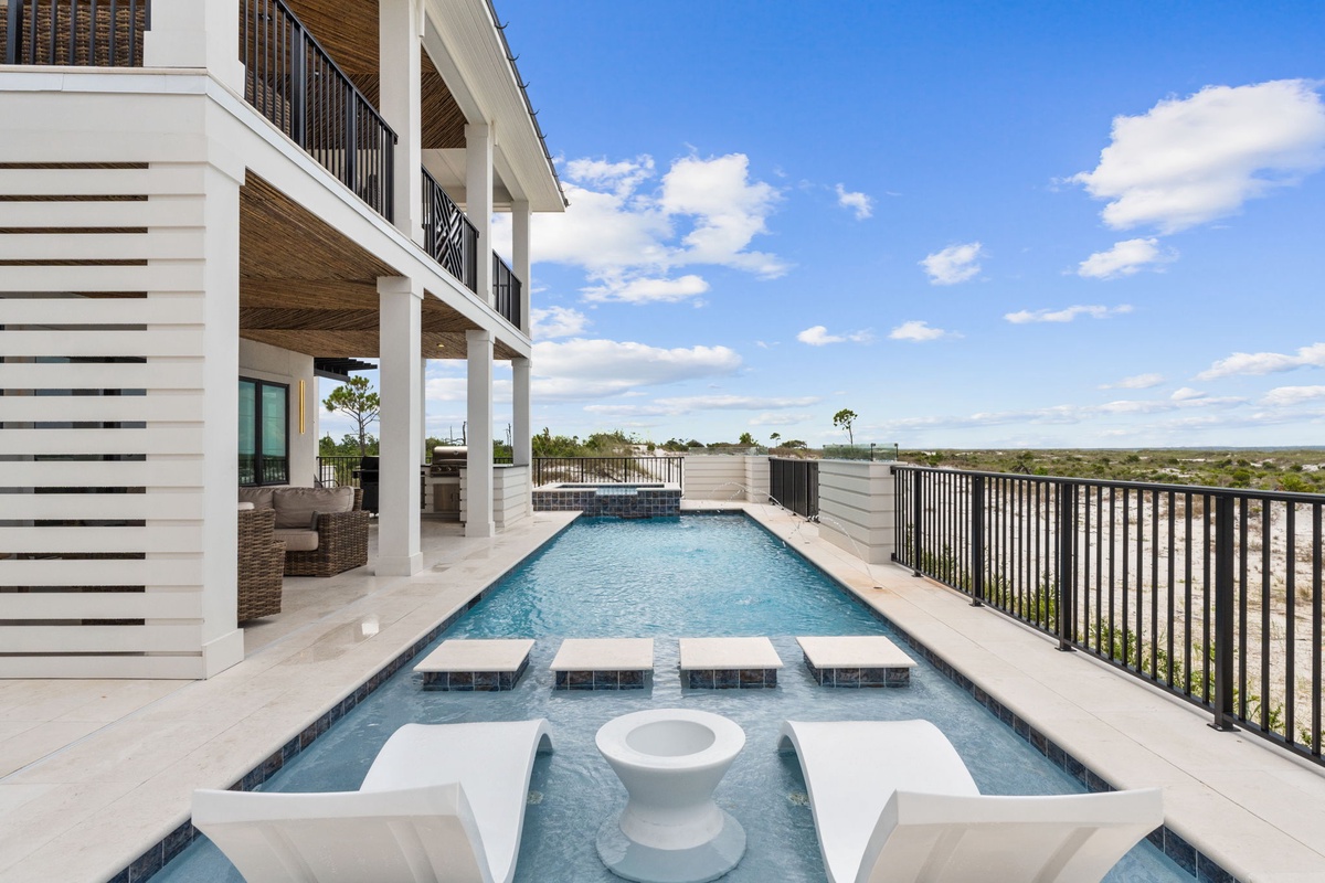 Stunning modern pool terrace with built-in seating overlooking expansive natural landscape views, offering an elevated outdoor retreat under open skies.
