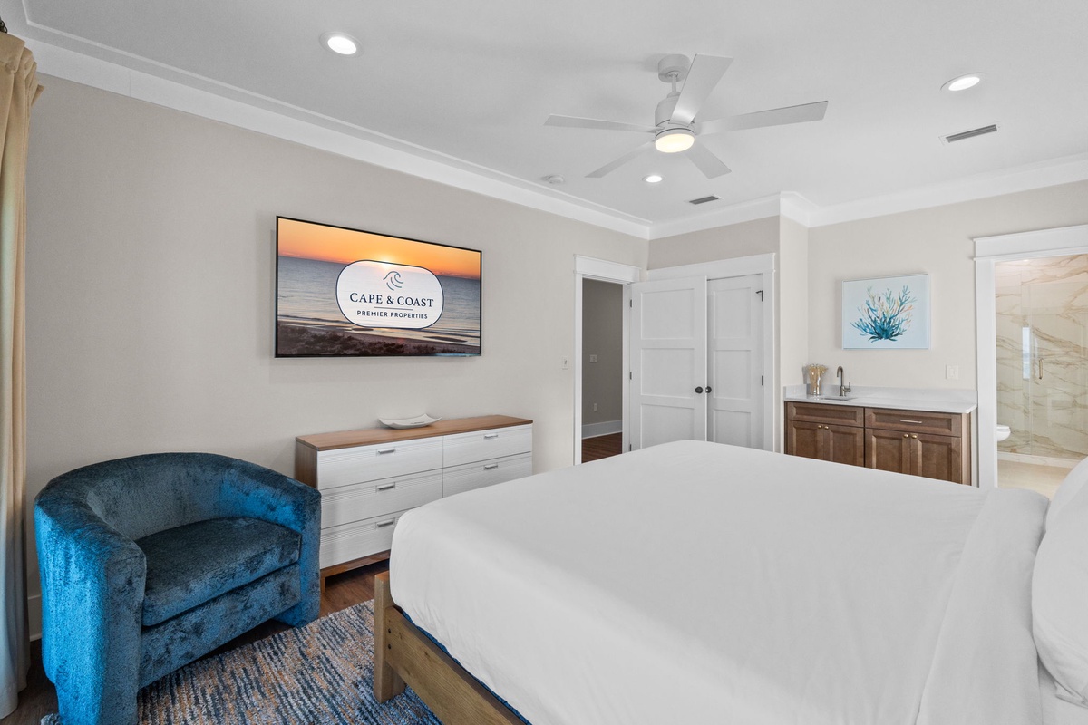 Your serene bedroom retreat features a plush king bed, cozy reading chair, and coastal artwork—your peaceful sanctuary for restful nights by the shore.