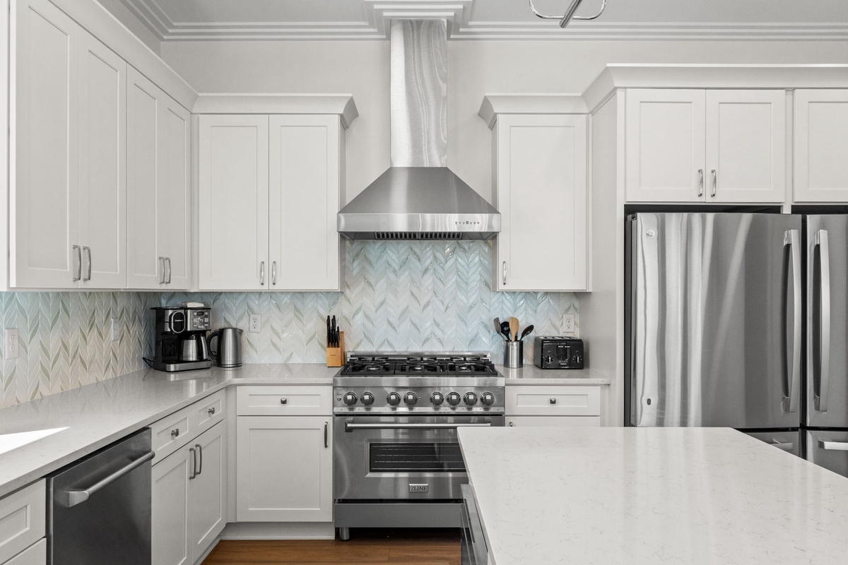 Step into your chef-inspired kitchen with gleaming stainless appliances, elegant white cabinetry, and a stunning herringbone backsplash that adds refined texture to your culinary space.