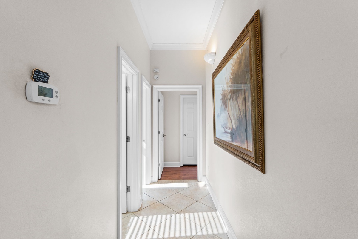 Step into your bright, welcoming hallway where coastal artwork and clean white doors guide you to your comfortable retreat spaces.