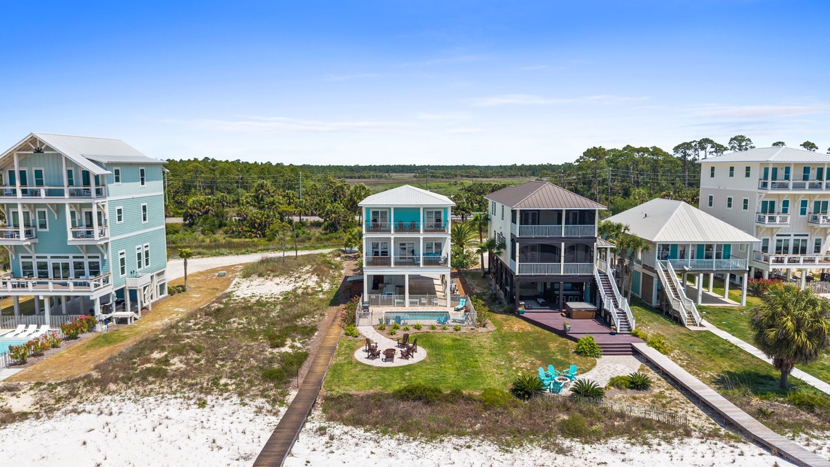 Aerial view of vacation rental homes nestled in a peaceful coastal neighborhood, surrounded by natural landscape and just steps from the beach.