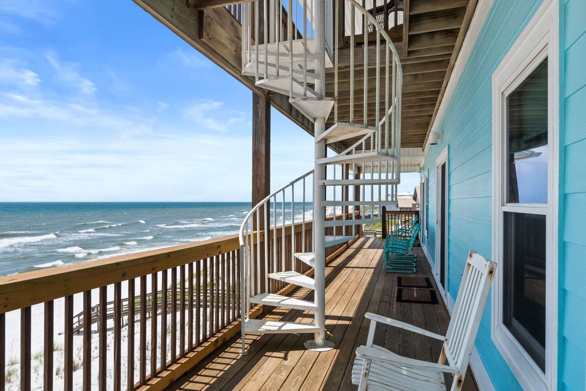 Beachfront deck with spiral staircase overlooking the sea. This multi-level outdoor space connects upper and lower levels of the property, providing direct coastal access.