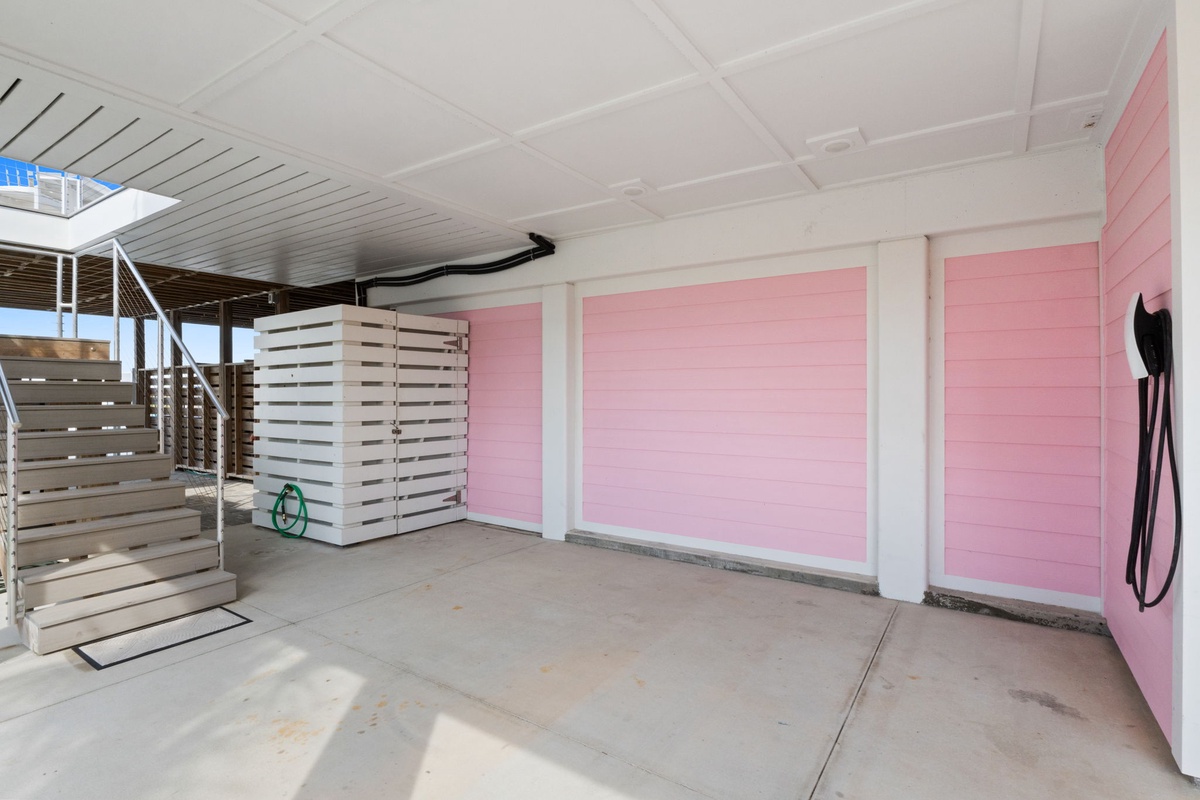 Modern covered outdoor area with storage and access to the property's main entrance. Clean concrete space with beach-style architectural details and convenient parking nearby.