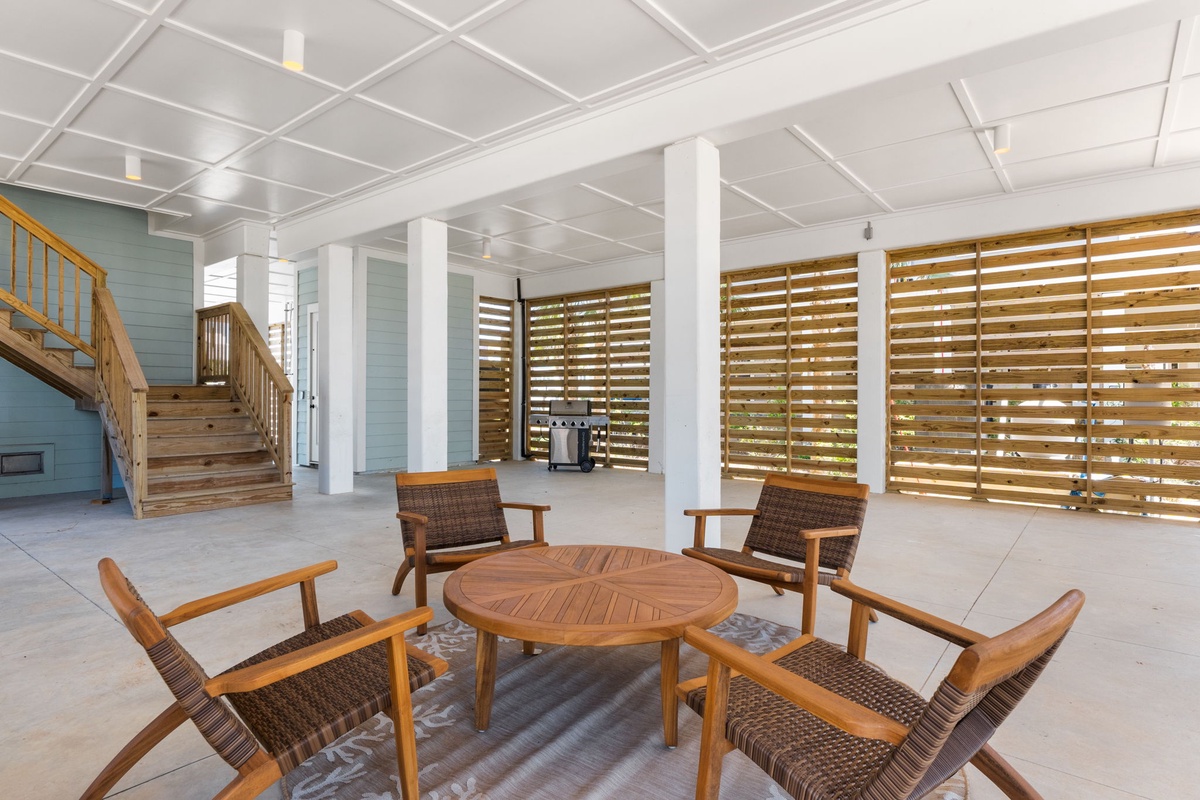 Relax in your private, covered patio area featuring stylish lounge seating and natural wood screens that filter gentle sunlight while maintaining privacy.