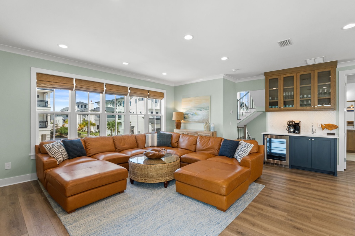 Sink into this inviting leather sectional where your mornings begin with coffee and coastal breezes. The wet bar is ready for evening cocktails as natural light floods the open space.
