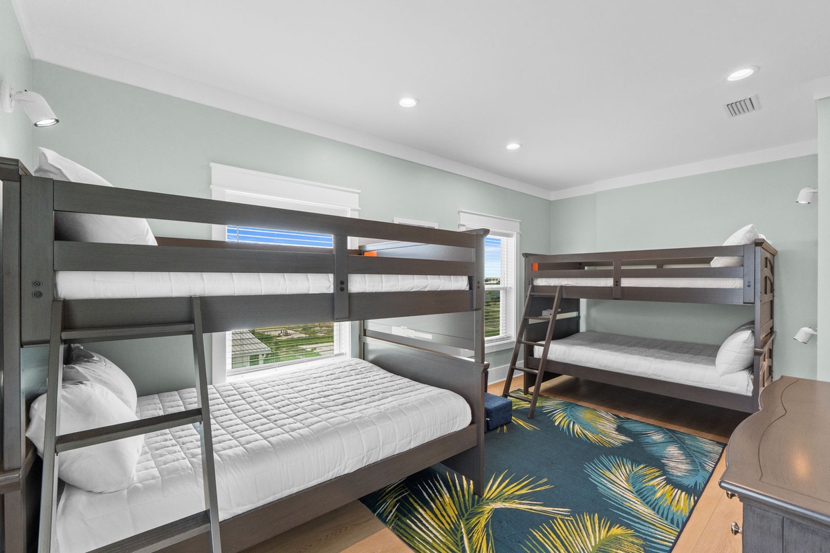 Your group will love this spacious bunk room with comfortable sleeping arrangements and cheerful tropical-themed decor welcoming everyone to rest after a day of adventure.