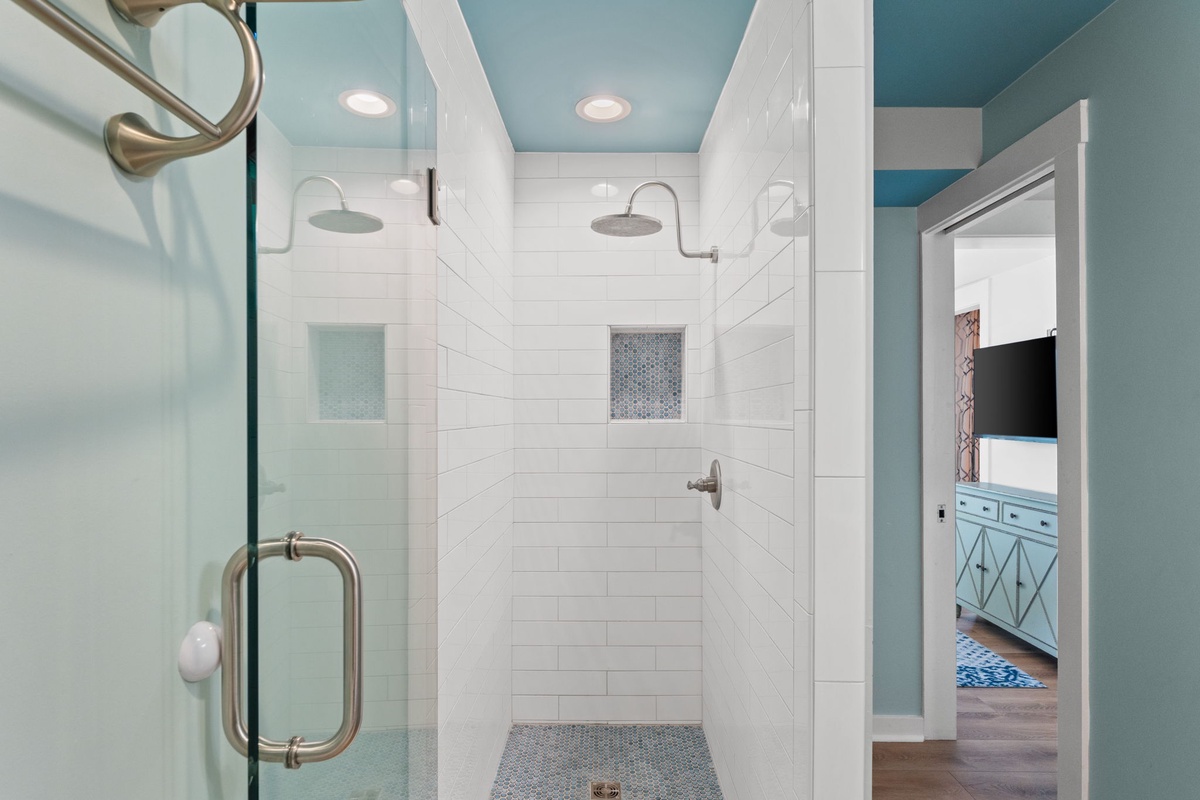 Step into your bright, spa-like walk-in shower with dual rainfall showerheads and elegant white subway tile. The serene blue ceiling adds a calming touch to your morning routine.
