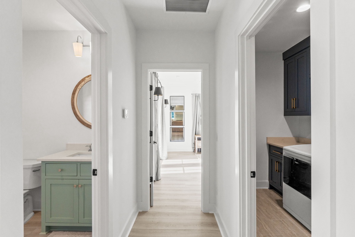 Discover your stylish hallway connecting thoughtfully designed spaces - from the charming mint vanity to the sleek kitchen beyond.