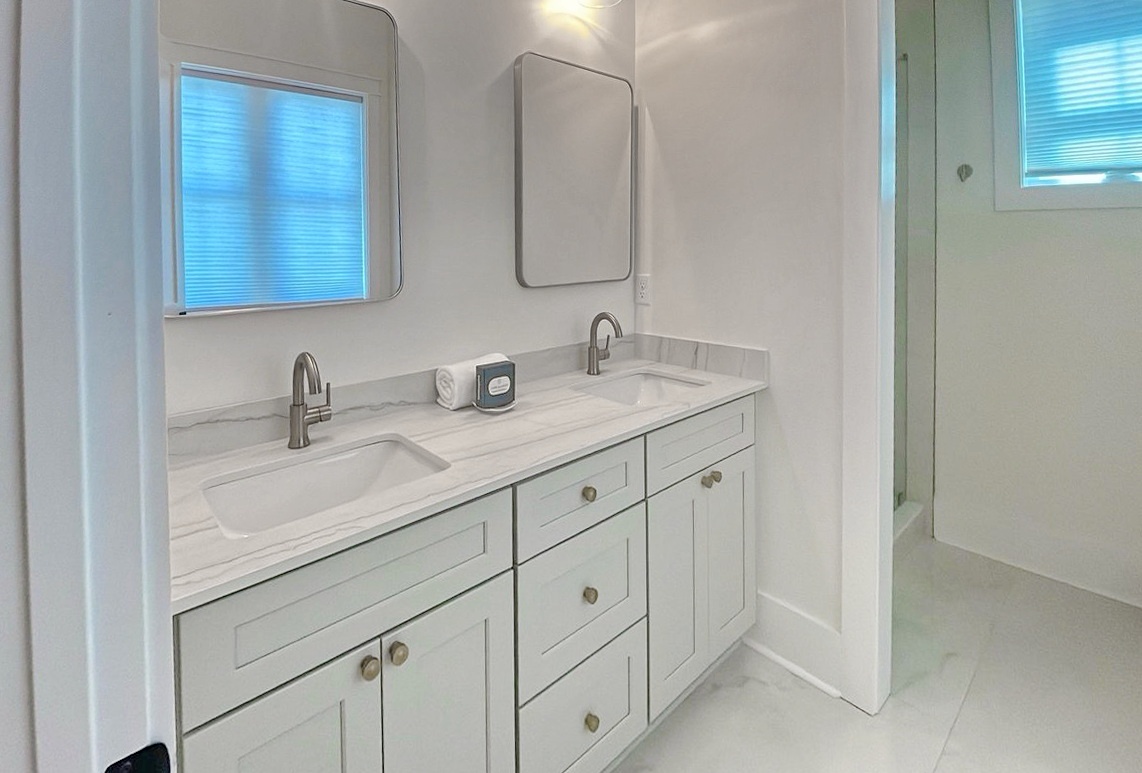 Bright and modern dual-sink vanity with elegant marble countertops, providing plenty of space and storage for your morning routine in this beautifully refreshed bathroom.
