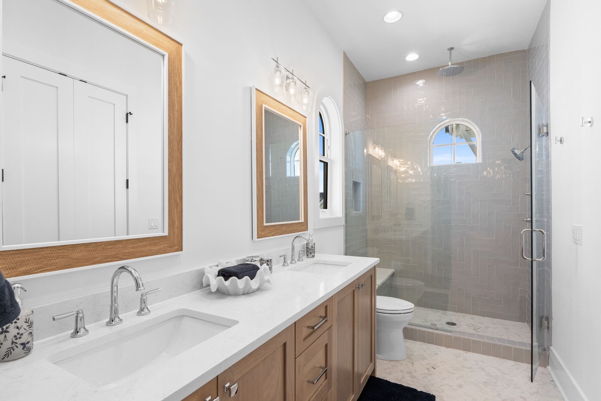 Unwind in your elegant bathroom featuring dual vanities, marble counters, and a luxurious glass shower with rainfall head.