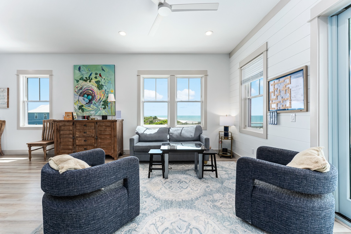 Sink into plush navy armchairs and soak up ocean views through bright windows in your coastal living room retreat.