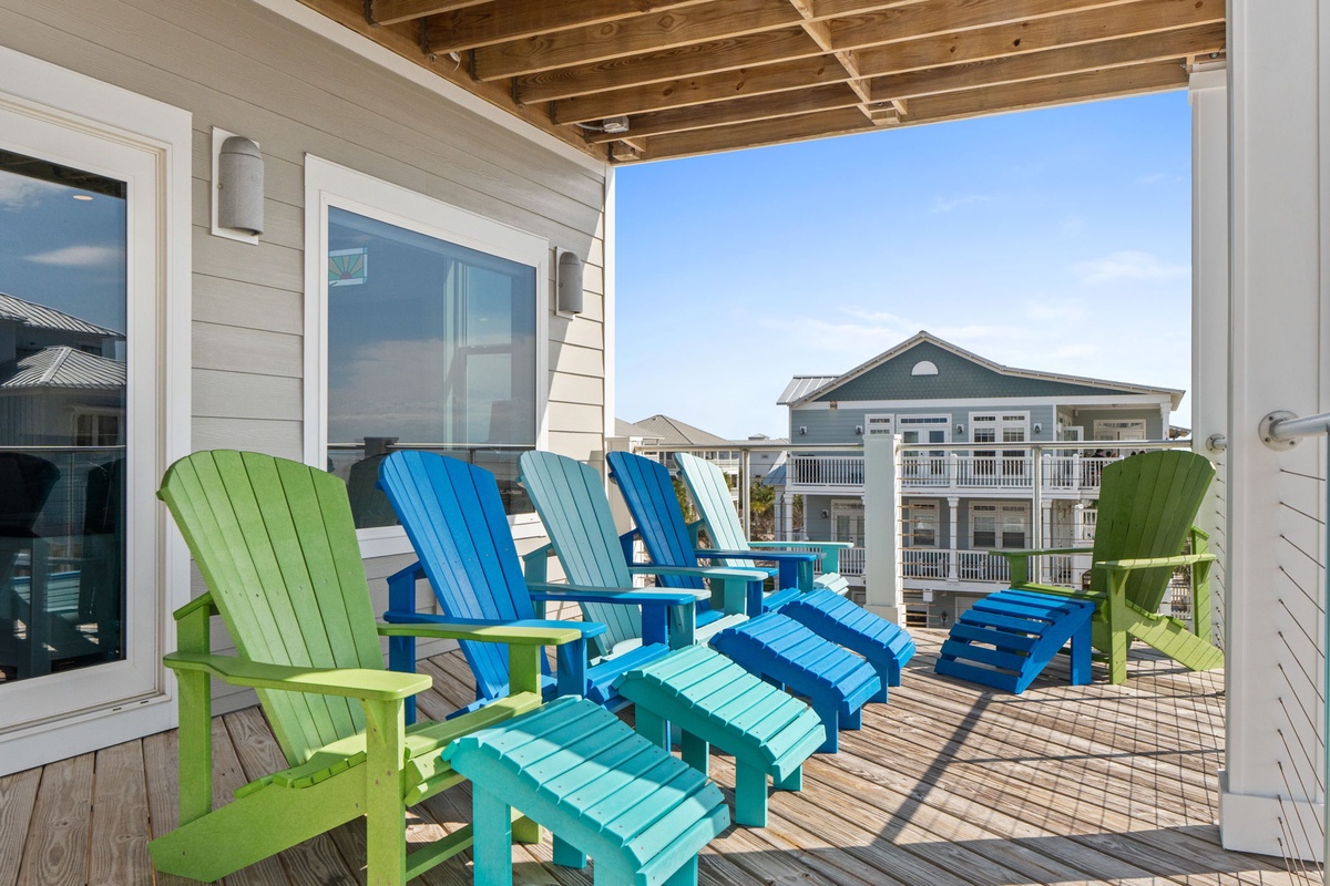 Unwind in vibrant beachside comfort on your private deck with colorful Adirondack chairs overlooking the coastal neighborhood.