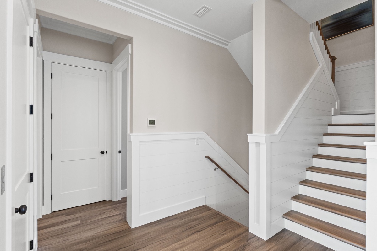 Elegant staircase and hallway with warm wood floors guide you between floors in this beautifully designed home.