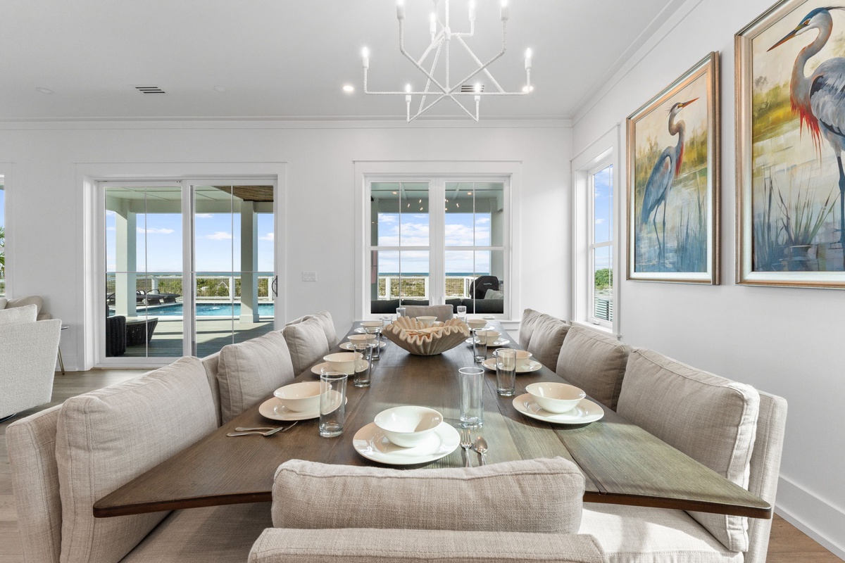 Gather around your elegant dining table where coastal artwork and natural light create the perfect setting for memorable meals together.